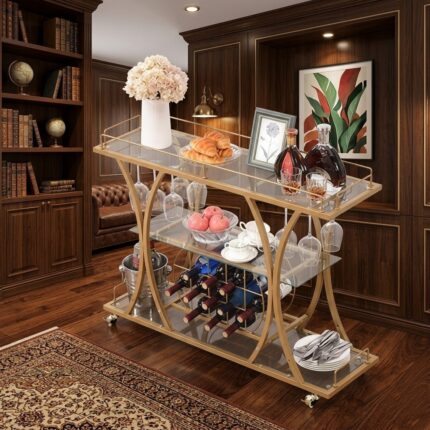 Upgrade your entertaining space with this Luxury Gold Bar Trolley Cart with Wine Rack, a perfect combination of elegance, functionality, and modern design. Crafted with a premium gold-finished metal frame and clear tempered glass shelves, this trolley adds a sophisticated touch to your living room, dining area, or home bar. The three-tier design provides ample storage and display space for wine bottles, glasses, snacks, and bar accessories. The built-in wine bottle rack securely stores multiple bottles, while the hanging glass holder keeps wine glasses organized and easily accessible. The spacious top shelf is ideal for serving drinks, desserts, or decorative items, making it perfect for entertaining guests. The sleek curved metal frame enhances the overall aesthetic appeal while maintaining durability and stability. Equipped with smooth rolling wheels, the trolley can be easily moved around your home, allowing convenient serving during parties, gatherings, or family events. Designed to blend beautifully with modern, contemporary, and luxury interiors, this bar trolley works as both a functional serving cart and a stylish décor element. Whether used as a wine trolley, drink cart, or kitchen serving trolley, it adds elegance and convenience to any space. Key Features: Premium gold-finished metal frame for a luxury look Three-tier tempered glass shelves for spacious storage Built-in wine rack for organized bottle storage Hanging glass holder for wine glasses Smooth rolling wheels for easy mobility Perfect for home bars, dining rooms, living rooms, and parties Stylish curved frame design for modern interiors